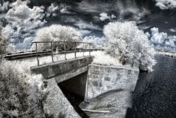 An infrared photo of a bridge over a river.