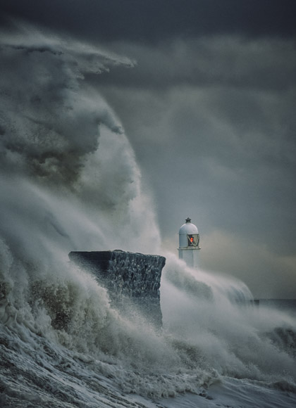 A large wave crashing over a lighthouse.