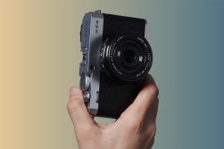 a person holding a Fuji X-E4 camera with lens attached in their hand.